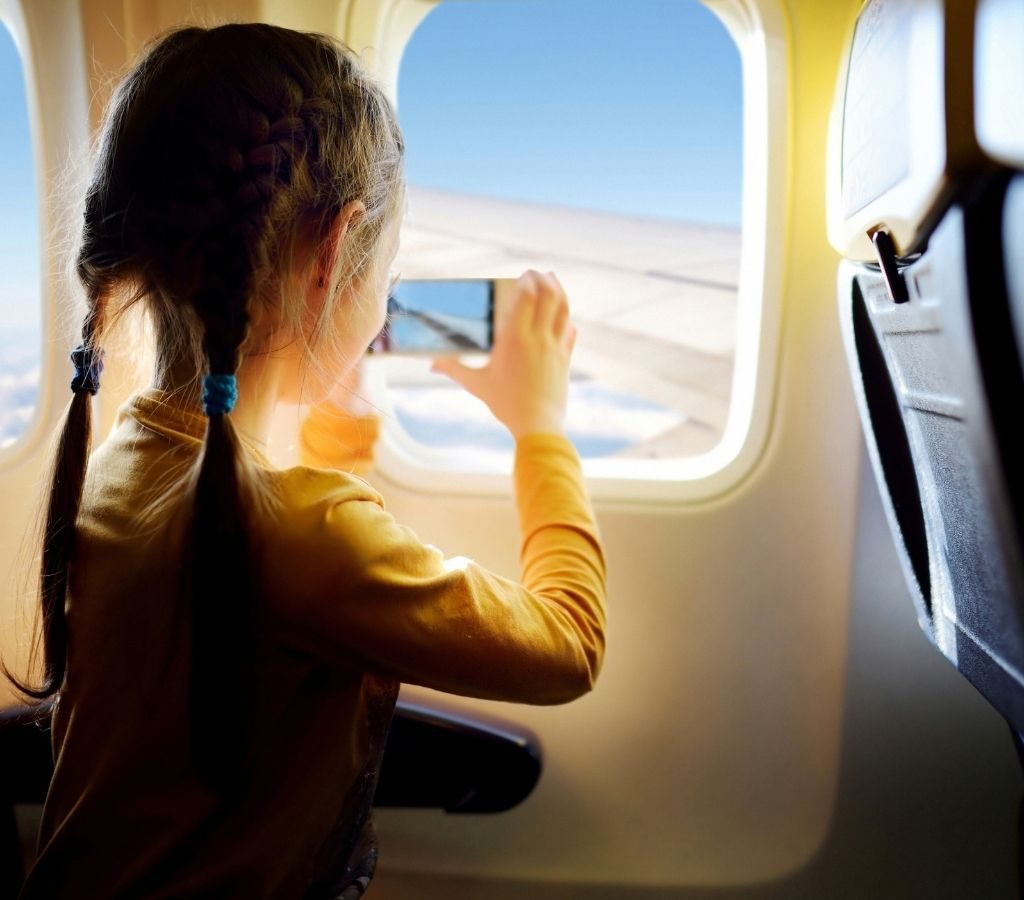 Child taking photo in airplane seat Photo Shutterstock